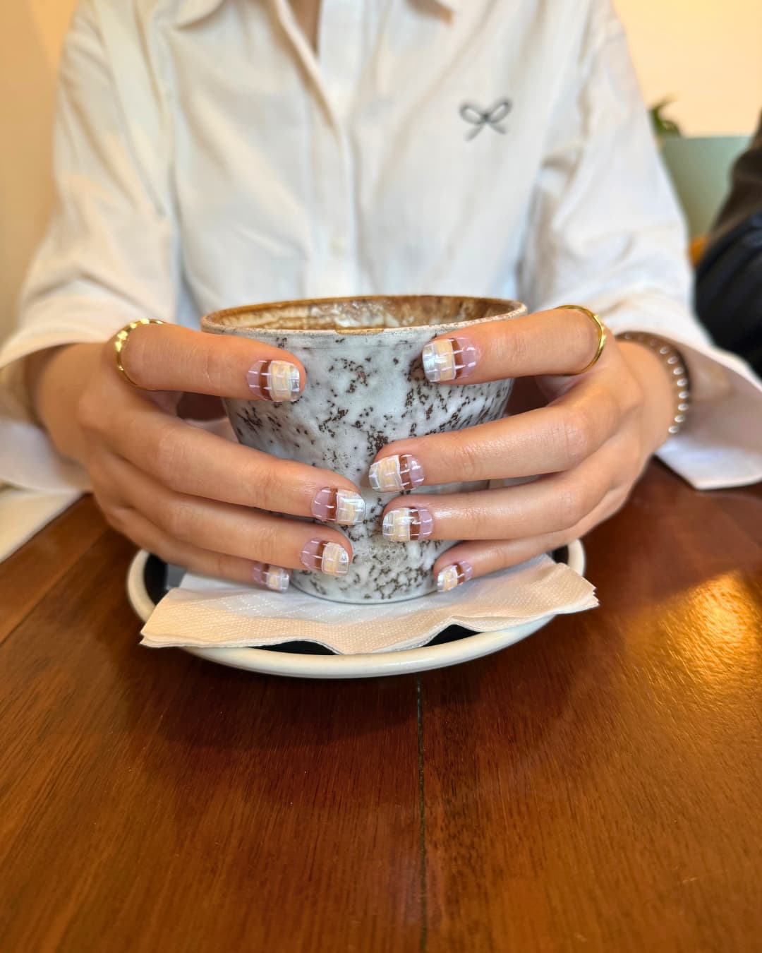 Lavender Glaze luxury press-on nails by Nailrative with glossy lilac finish, styled in a cozy café moment holding coffee.