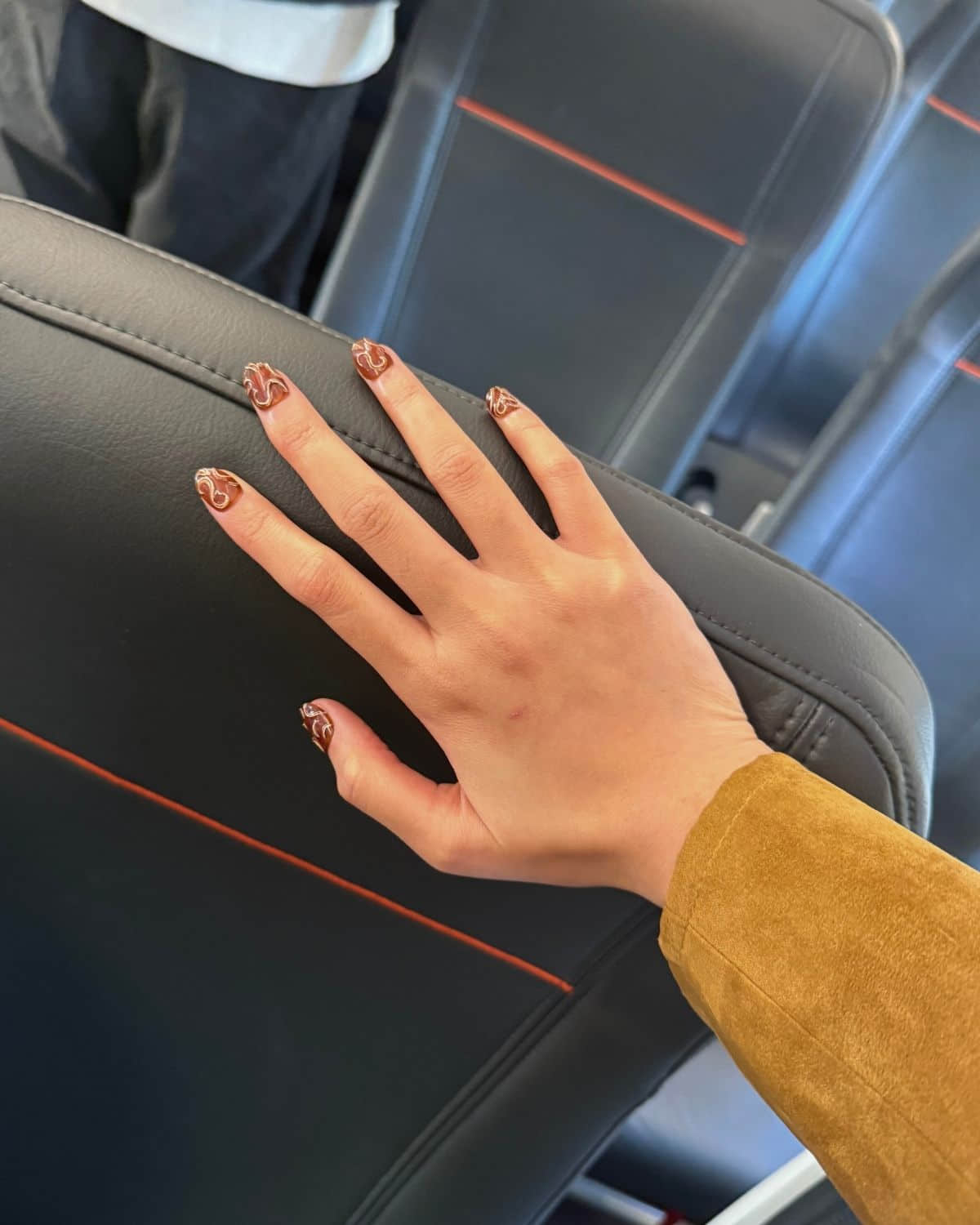 Press-on nails resting on airplane seat during travel.