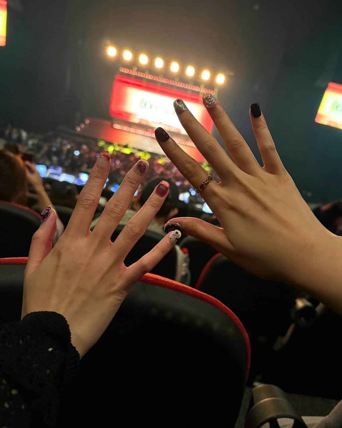 Monochrome Orbit luxury press-on nails by Nailrative with black and silver 3D designs, shown at a live concert under stage lights. Stylish manicure with pearl and swirl accents, perfect for nightlife, music events, and bold fashion moments.