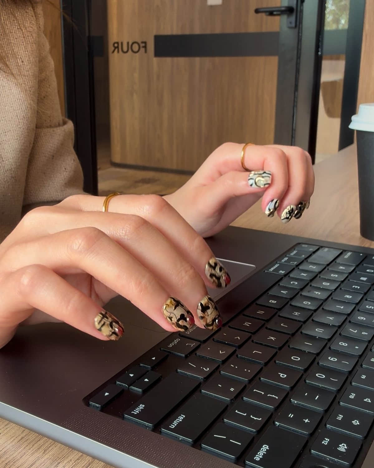 Reusable press-on nails styled with laptop and coffee cup for a chic workday look.